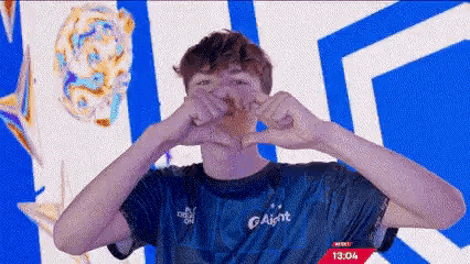 a man in a blue shirt is making a heart shape with his hands in front of a blue and white background .