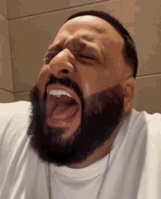 a man with a beard is laughing with his mouth wide open .