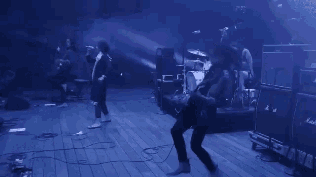 a group of people playing instruments on a stage with blue lights