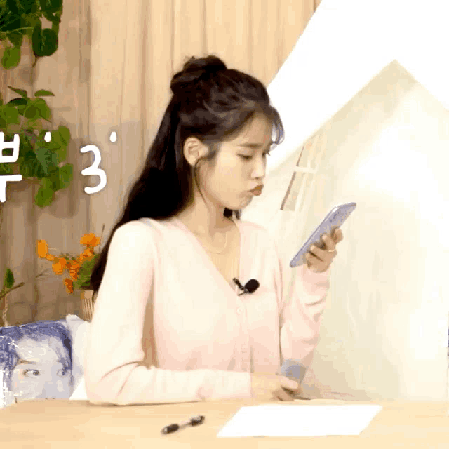 a woman sitting at a table looking at a cell phone with the number 3 in the background