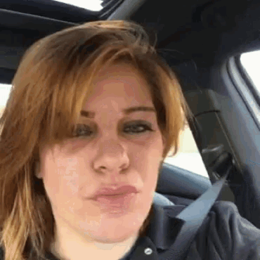 a woman is sitting in a car wearing a seat belt .