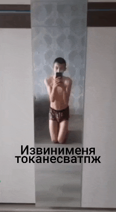 a man is kneeling down in front of a mirror taking a selfie with his phone .