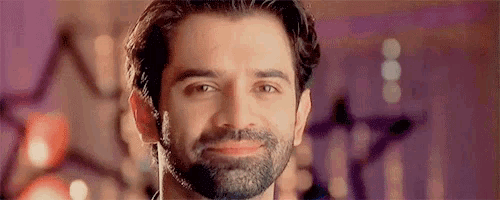 a close up of a man with a beard smiling in front of a purple background .