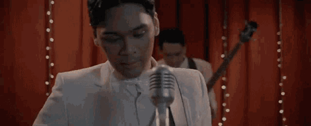 a man in a suit singing into a microphone with the words tak bisa kupercaya behind him