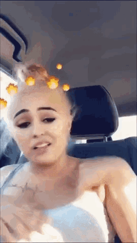 a woman with a tattoo on her chest is sitting in a car .
