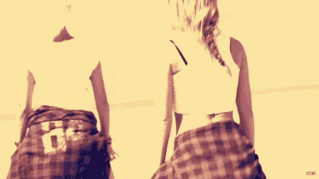 two women in plaid skirts are dancing in front of a yellow background with a red r on it