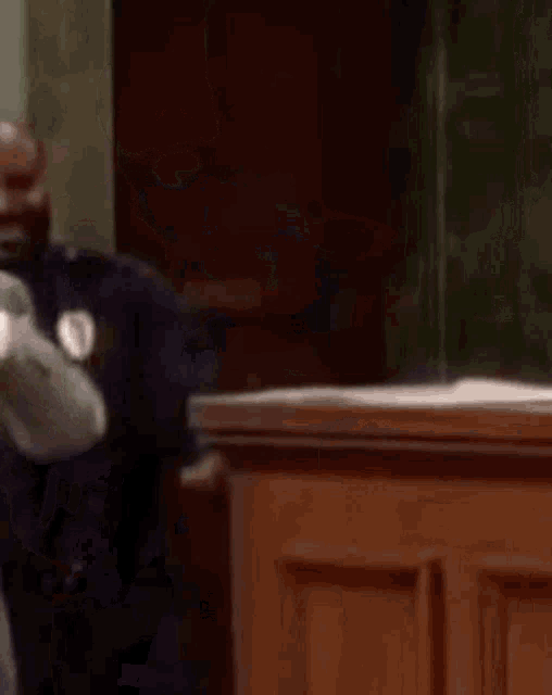 a police officer is talking to a man in a suit while standing next to a wooden counter .