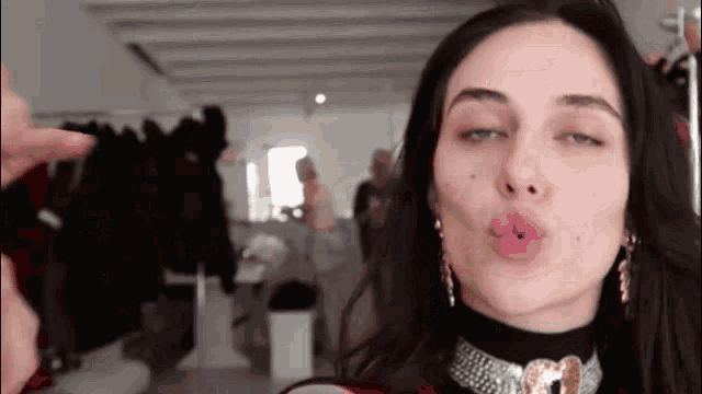 a woman wearing a choker is blowing a kiss at the camera