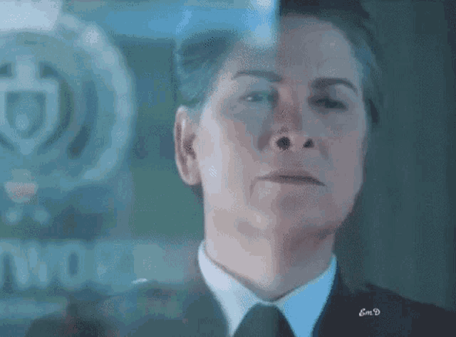 a woman in a suit and tie is looking through a glass door .