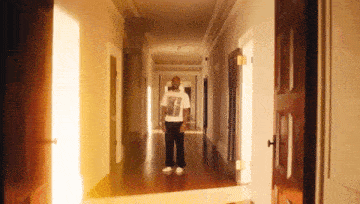 a man in a white shirt is standing in a long hallway