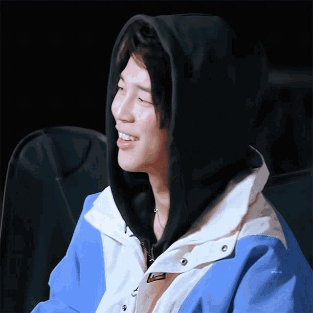 a person wearing a blue and white jacket with a black hood on their head