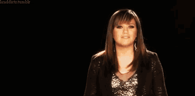 a woman in a black jacket stands in front of a black background with the words kaddicts tumblr at the top