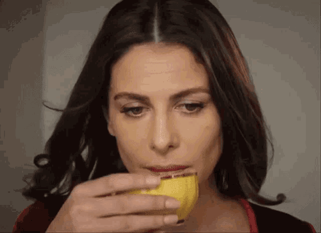 a woman is drinking a slice of lemon from a cup