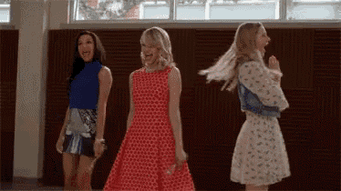 three women are standing next to each other in a room and dancing .