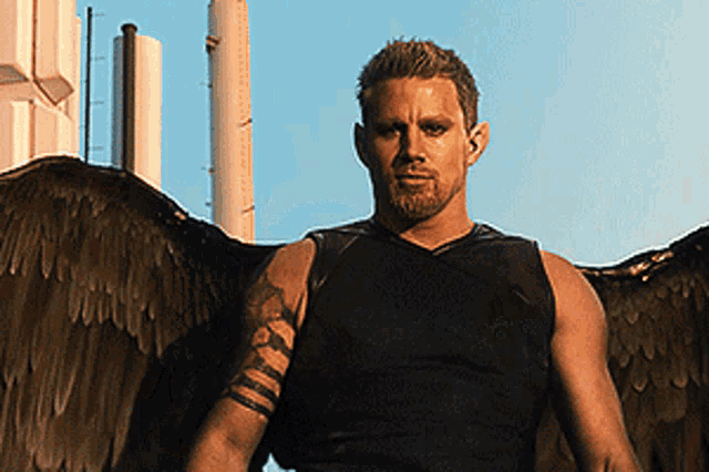 a man with a tattoo on his arm is wearing a black tank top with wings