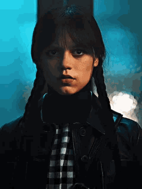 a girl with pigtails and a plaid shirt is wearing a black leather jacket