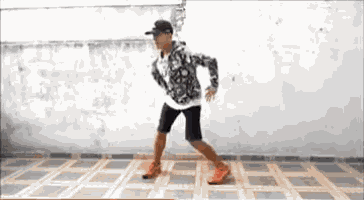 a young boy is dancing on a tiled floor in front of a wall .