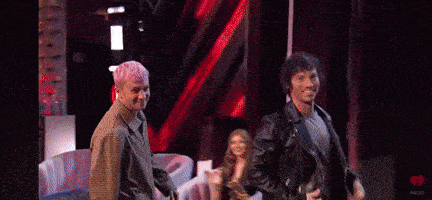 a man with pink hair is standing next to a man in a leather jacket on a stage