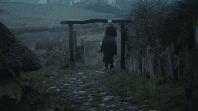 a person riding a horse down a path with a thatched roof