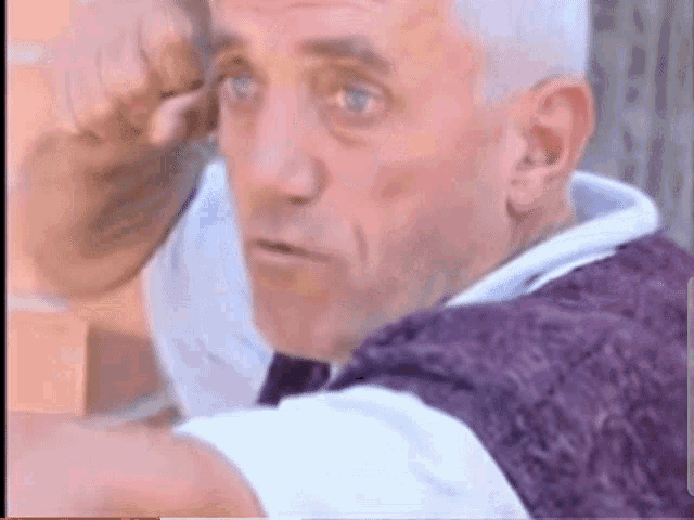 a man with gray hair is wearing a white shirt and purple vest
