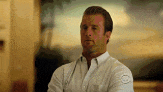 a man in a white shirt is standing with his arms crossed and making a funny face .