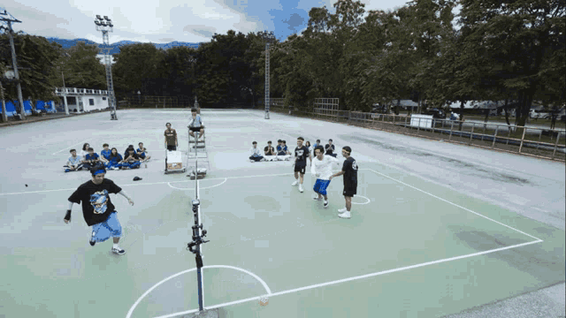 a group of people are playing a game of basketball on a court with a referee in the background