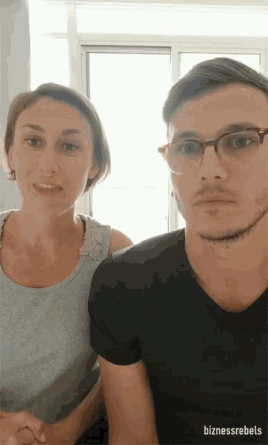a man and a woman are standing next to each other and the man has glasses