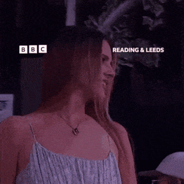 a woman is smiling in front of a sign that says " watch on iplayer "