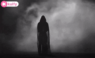 a silhouette of a person in a hooded cape standing in the fog