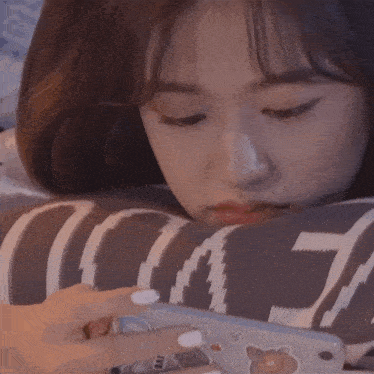 a woman laying on a pillow looking at her phone with a sticker on it that says i love you