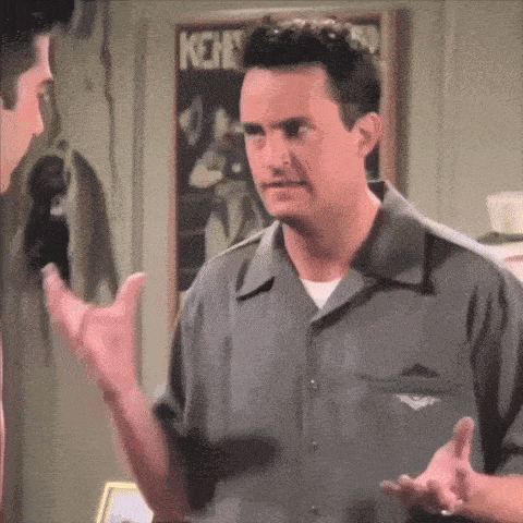 a man in a grey shirt talking to another man in front of a sign that says kehs