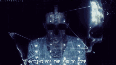 a man is standing in front of a screen with the words `` waiting for the end to come '' displayed on it .