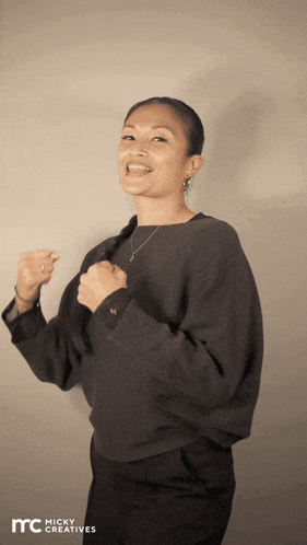 a woman with her fist in the air and the words micky creatives on the bottom right