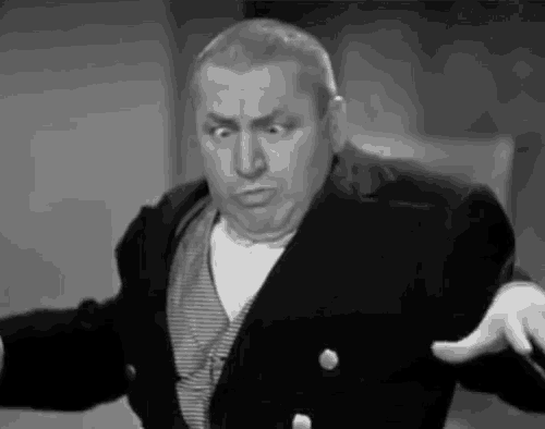 a black and white photo of a man in a suit and tie making a funny face .