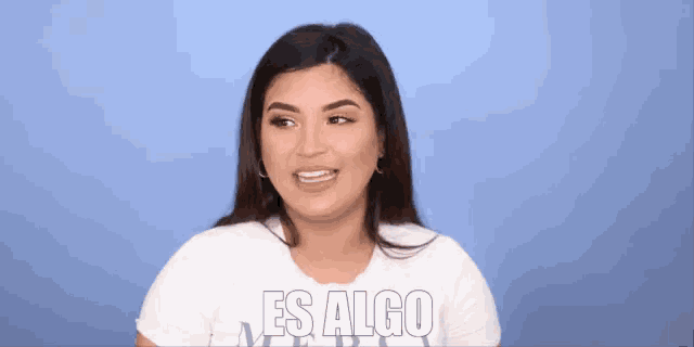 a woman wearing a white shirt with the words es algo on it