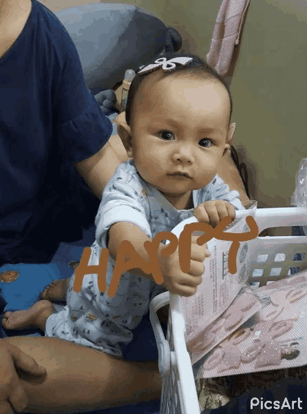 a baby is sitting next to a basket that says happy on it