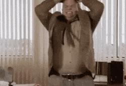 a man in a suit and tie is standing in front of a window with his hands on his head .