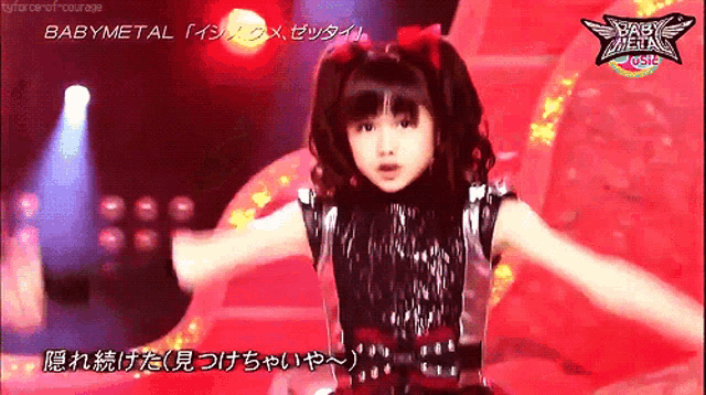 a girl is dancing on a stage with a babymetal logo on the bottom right