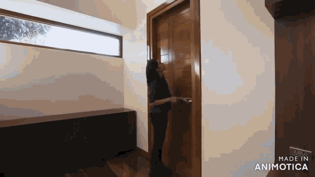 a woman opens a wooden door in a room made in animatica