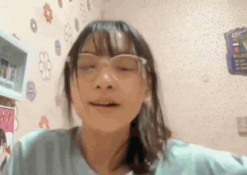 a girl wearing glasses is making a funny face in front of a wall with flowers on it .