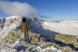 a person standing on top of a snow covered mountain .