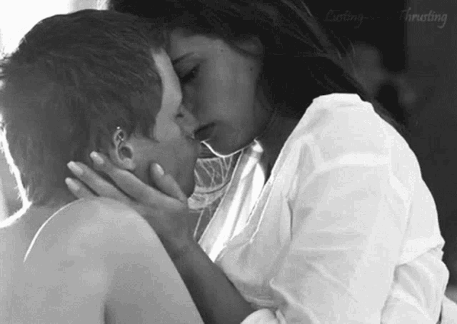 a black and white photo of two women kissing each other .