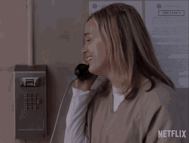 a woman is smiling while talking on a phone in front of a netflix poster