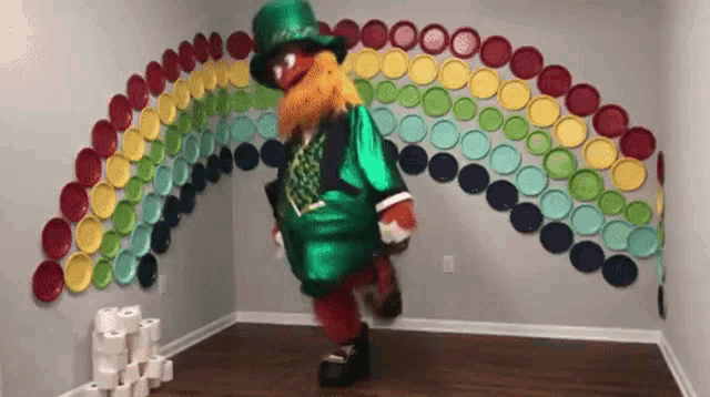 a leprechaun mascot is dancing in front of a rainbow made of plates on the wall .
