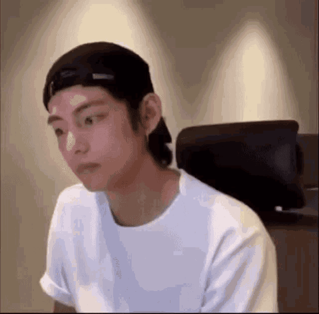 a young man wearing a baseball cap is sitting in a chair .