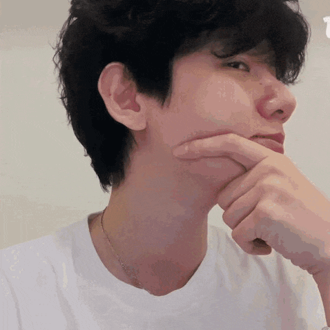 a young man is holding his hand to his chin .
