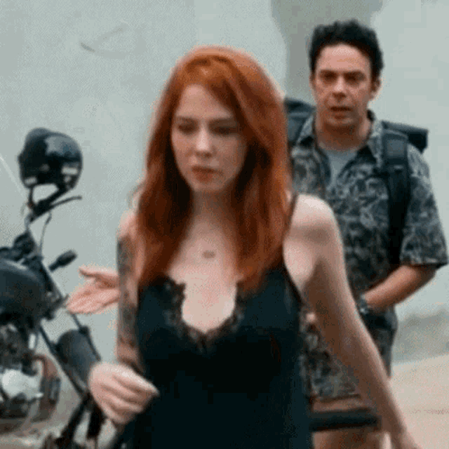 a man and a woman are standing in front of a motorcycle ..