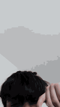 a man with dark hair is holding a white object in his hand