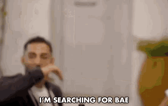 a man in a suit is saying `` i 'm searching for bae '' in a blurry photo .