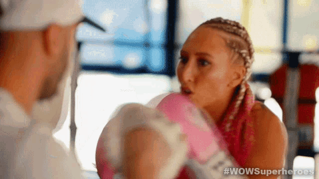 a woman is wearing pink boxing gloves and talking to a man .